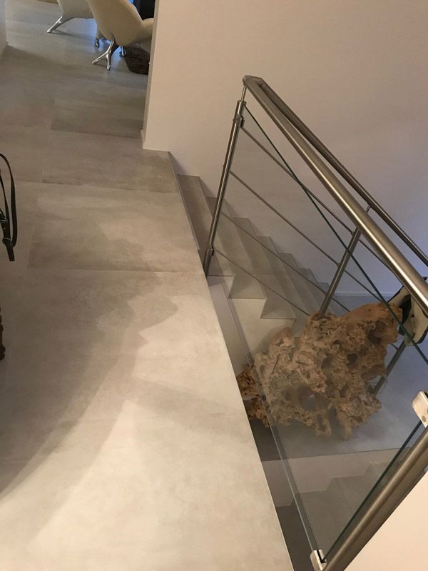 Un escalier avec une rampe en acier inoxydable et une rampe en verre