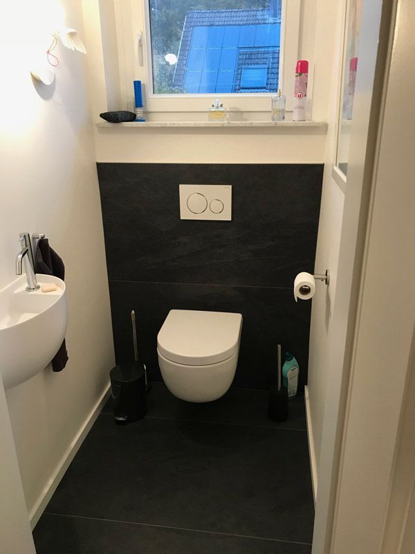 Une petite salle de bain avec WC, lavabo et fenêtre.