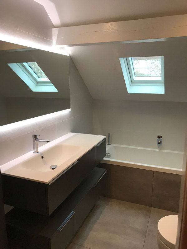 Une salle de bain avec lavabo, baignoire, toilettes et puits de lumière