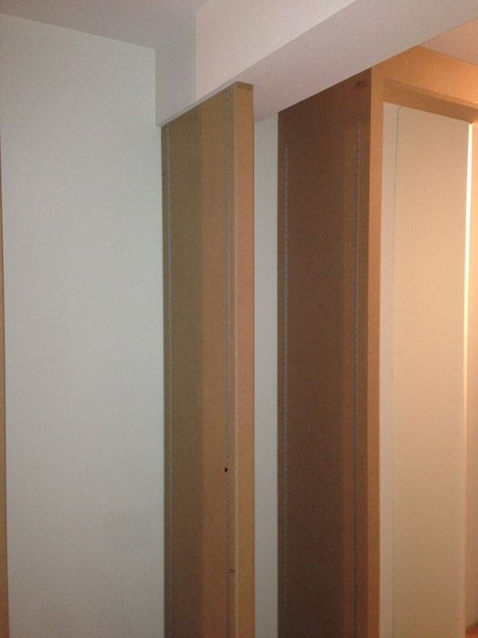 Un couloir avec deux portes en bois et un mur blanc.