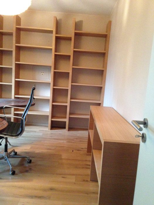 Une pièce avec des étagères en bois, un bureau et une chaise