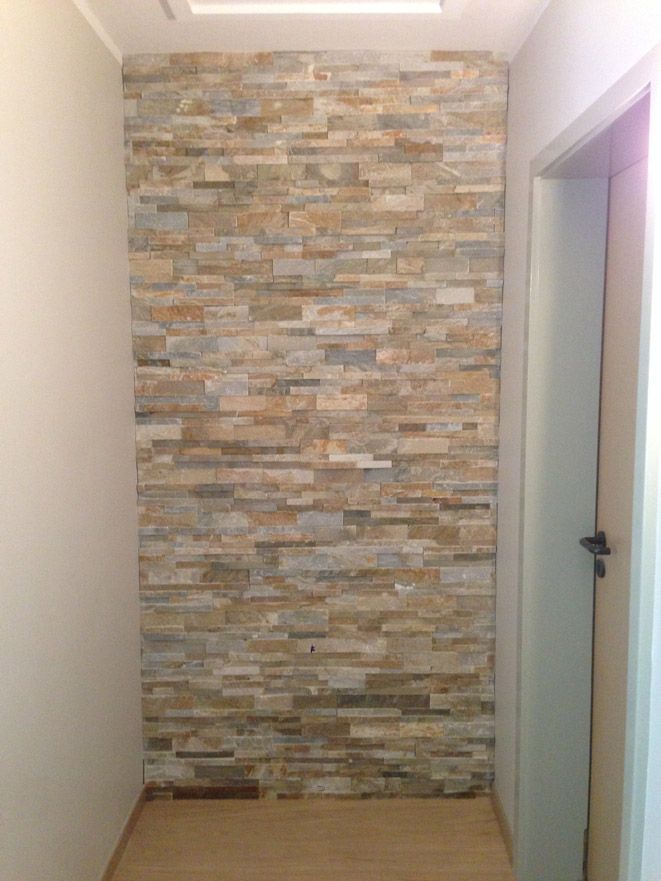 Un couloir avec un mur en pierre et une porte.