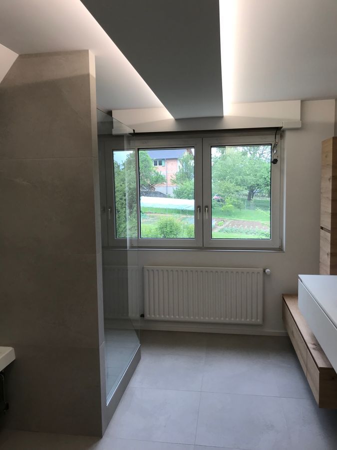 Une salle de bain avec une grande fenêtre et un radiateur.