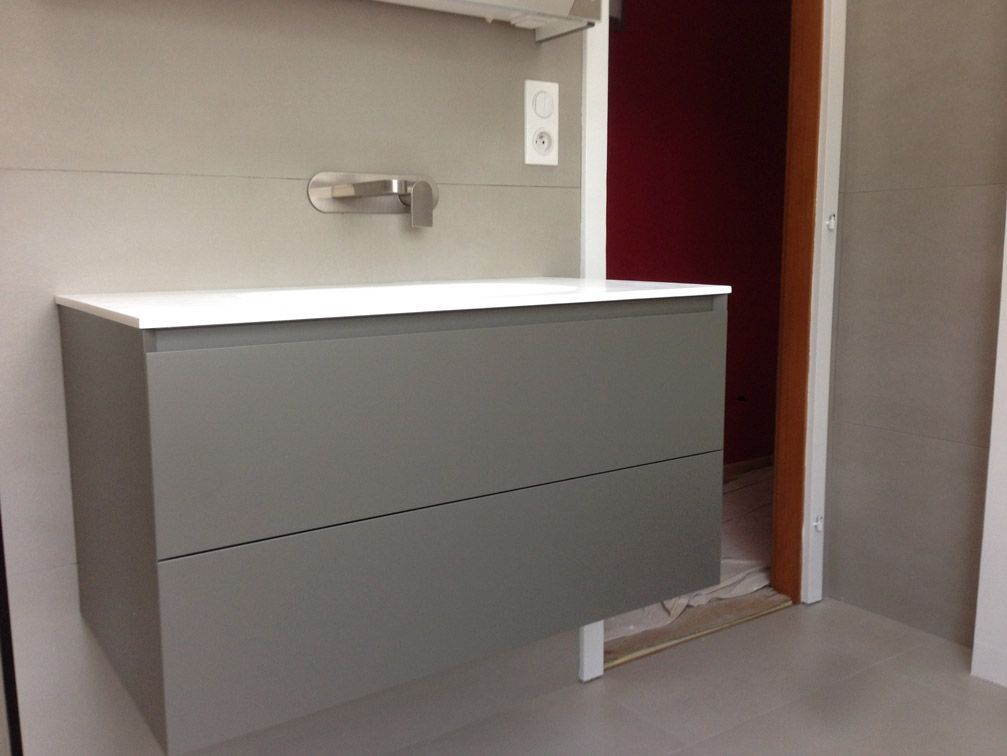 Une salle de bain avec une vanité grise et un lavabo blanc