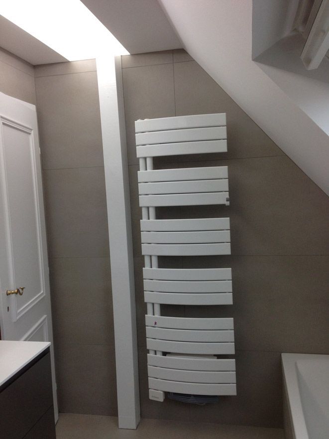 Un porte-serviettes blanc est accroché au mur d'une salle de bain.