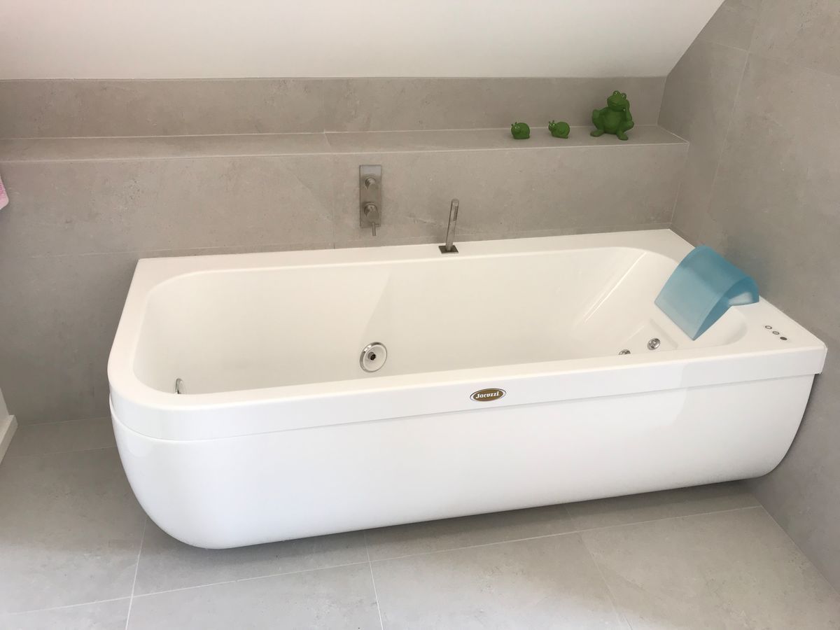 Une grande baignoire blanche se trouve dans une salle de bain.