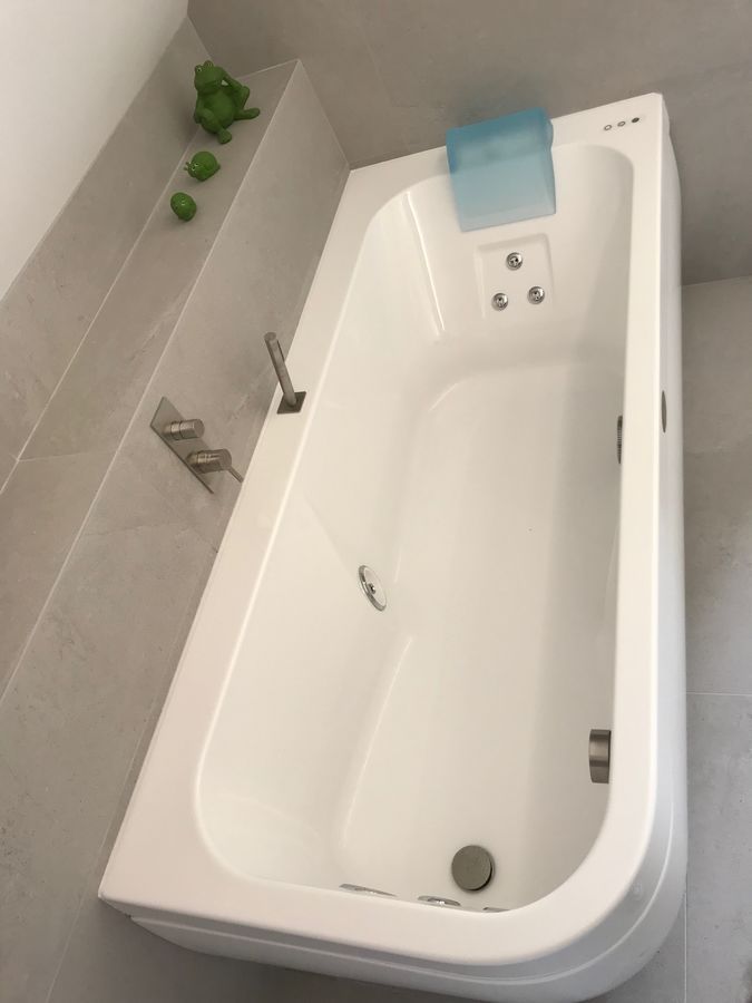 Une baignoire blanche dans une salle de bain avec des grenouilles sur le mur
