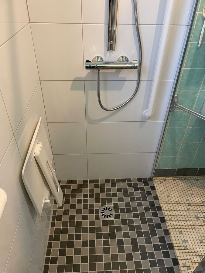 Une douche à l'italienne avec un sol carrelé et une pomme de douche.