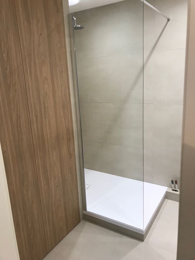 Une salle de bain avec une douche à l'italienne et une porte en bois.