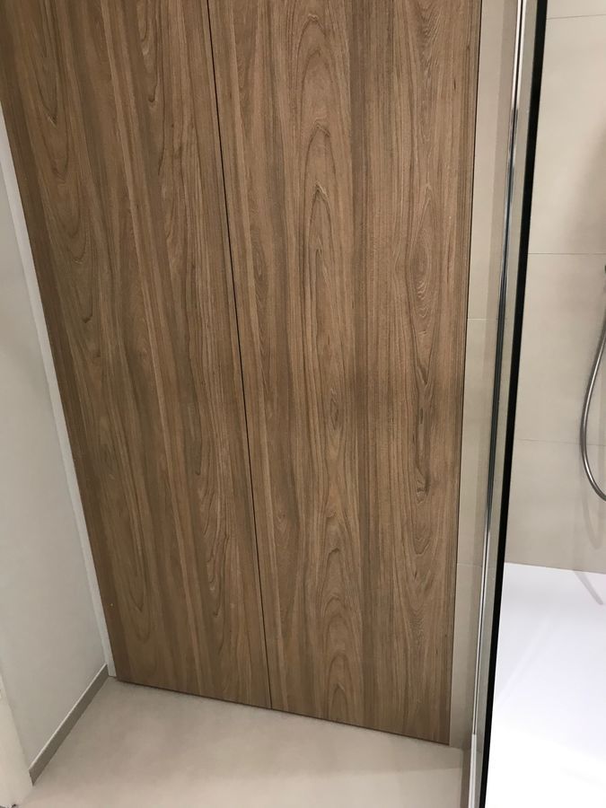 Une salle de bain avec un mur en bois et une porte de douche en verre.