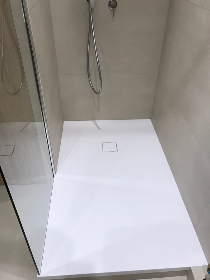 Une cabine de douche blanche avec une pomme de douche dans une salle de bain.