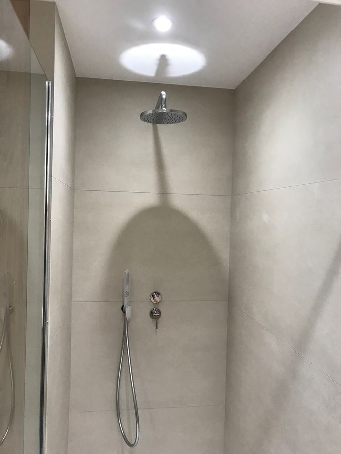 Une pomme de douche est suspendue au plafond dans une salle de bain.