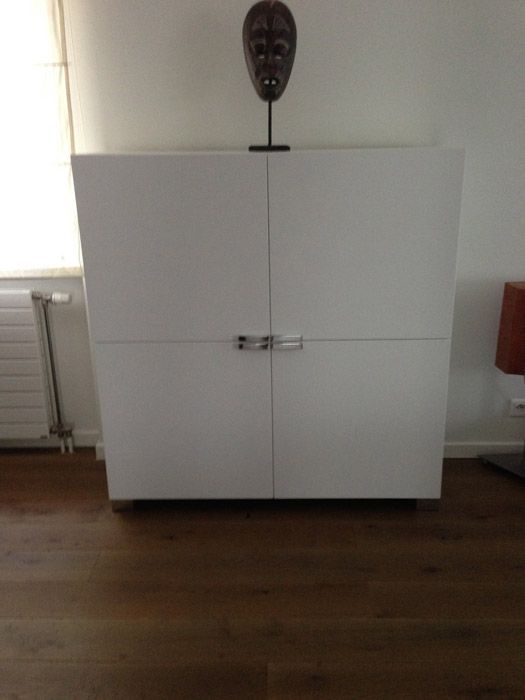 Une armoire blanche avec un masque dessus dans un salon.