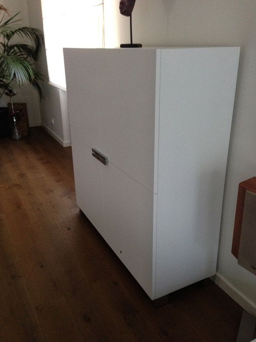 Une armoire blanche est posée sur un plancher en bois dans un salon.