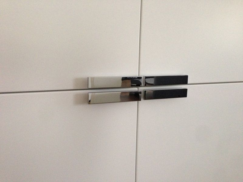 Un gros plan d'une armoire blanche avec des poignées chromées