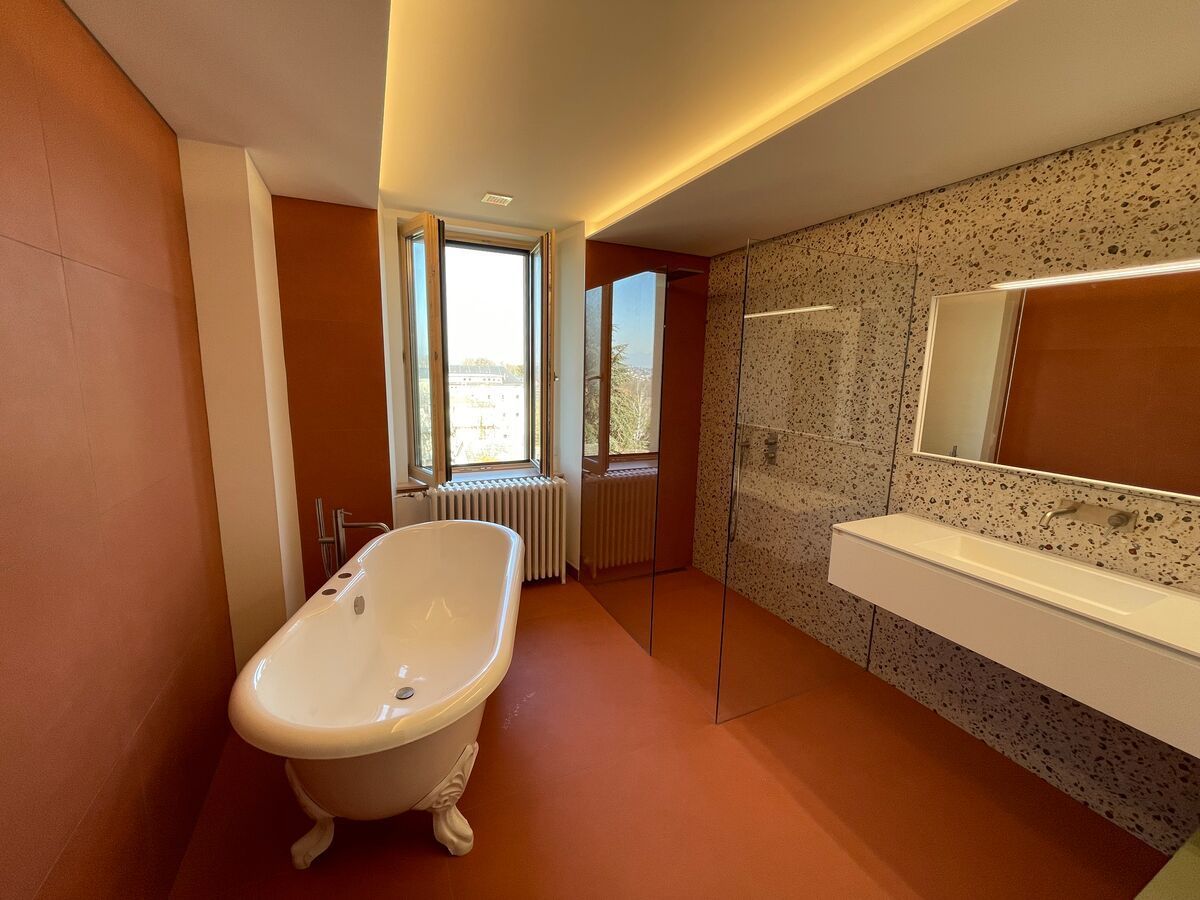 Une salle de bain avec baignoire, lavabo, miroir et fenêtre.