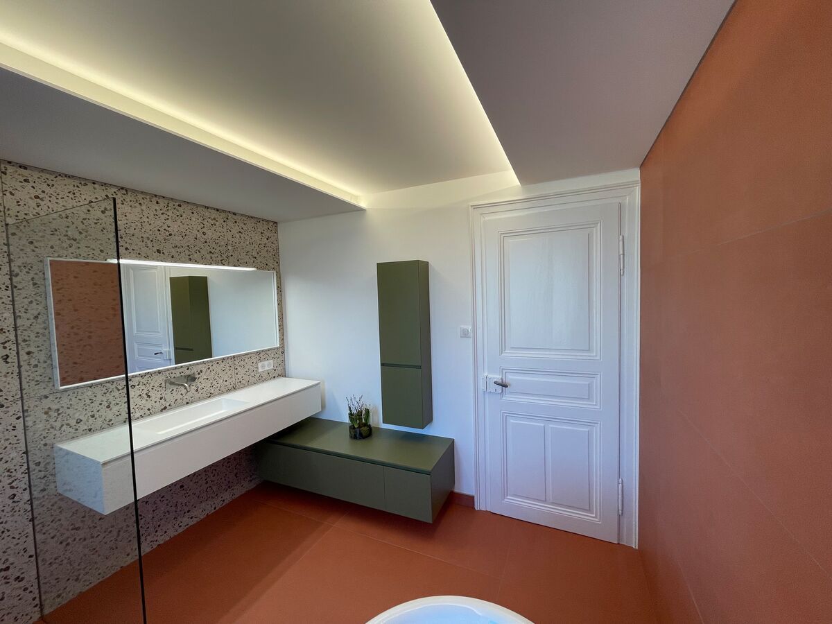 Une salle de bain avec baignoire, lavabo, miroir et porte.