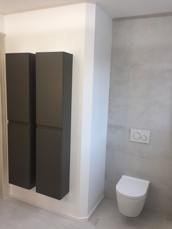 Une salle de bain avec deux armoires noires et des toilettes