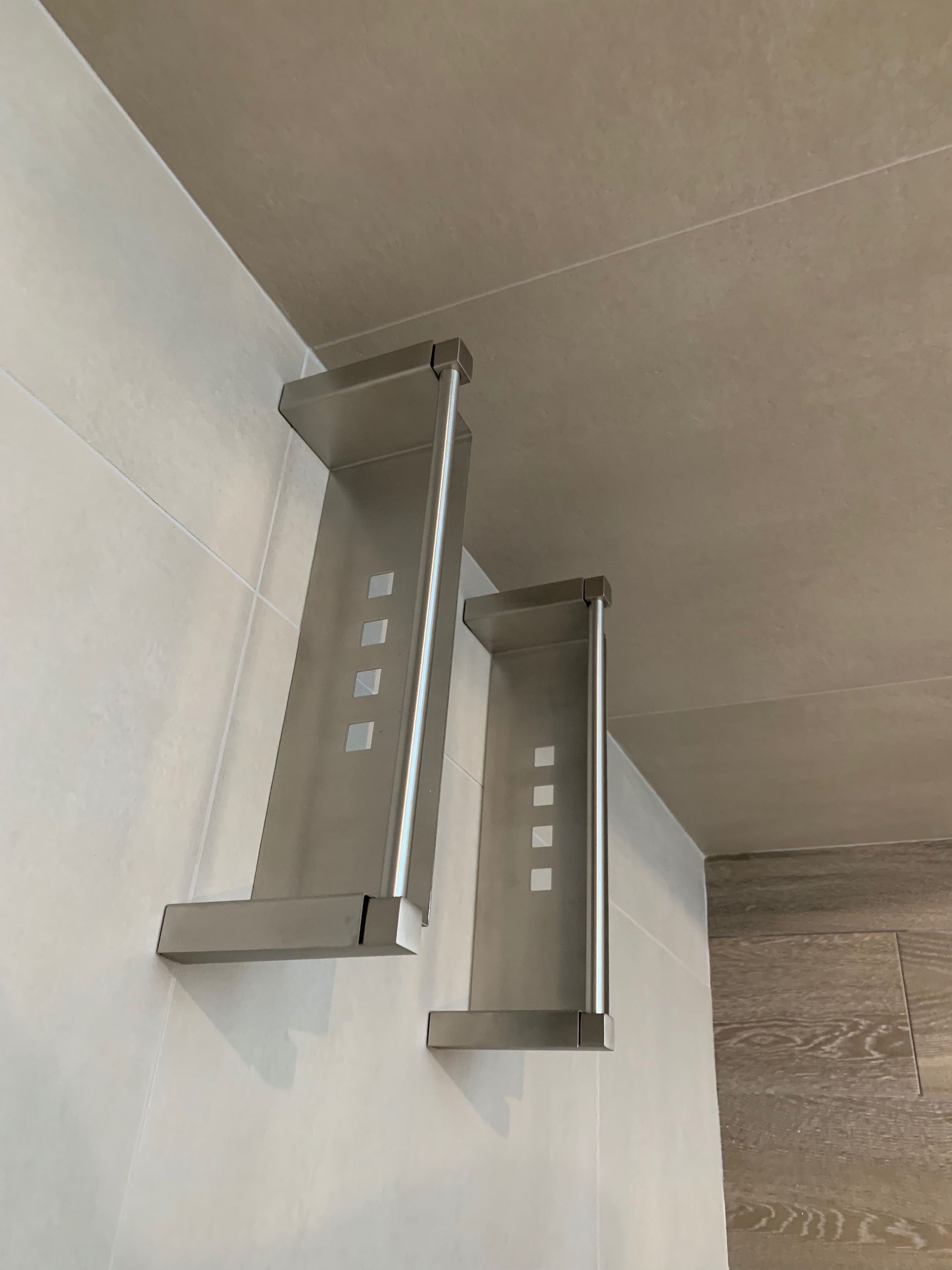 Deux étagères en acier inoxydable sont accrochées à un mur.