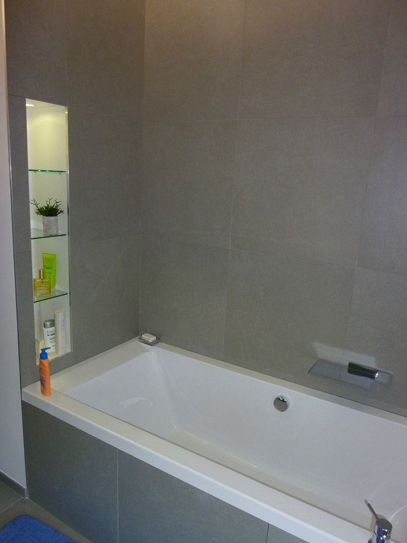 Une baignoire dans une salle de bain avec une étagère derrière