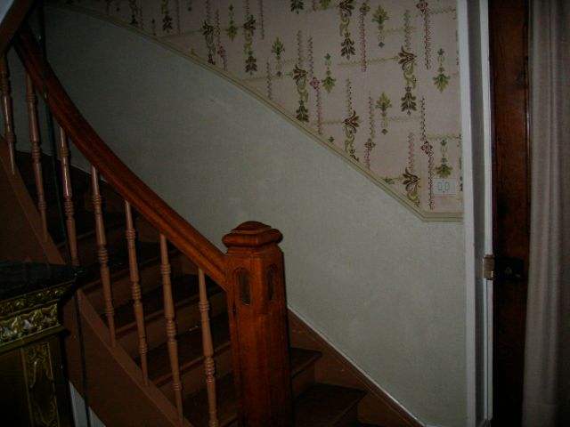 Un escalier en bois avec un papier peint floral sur le mur