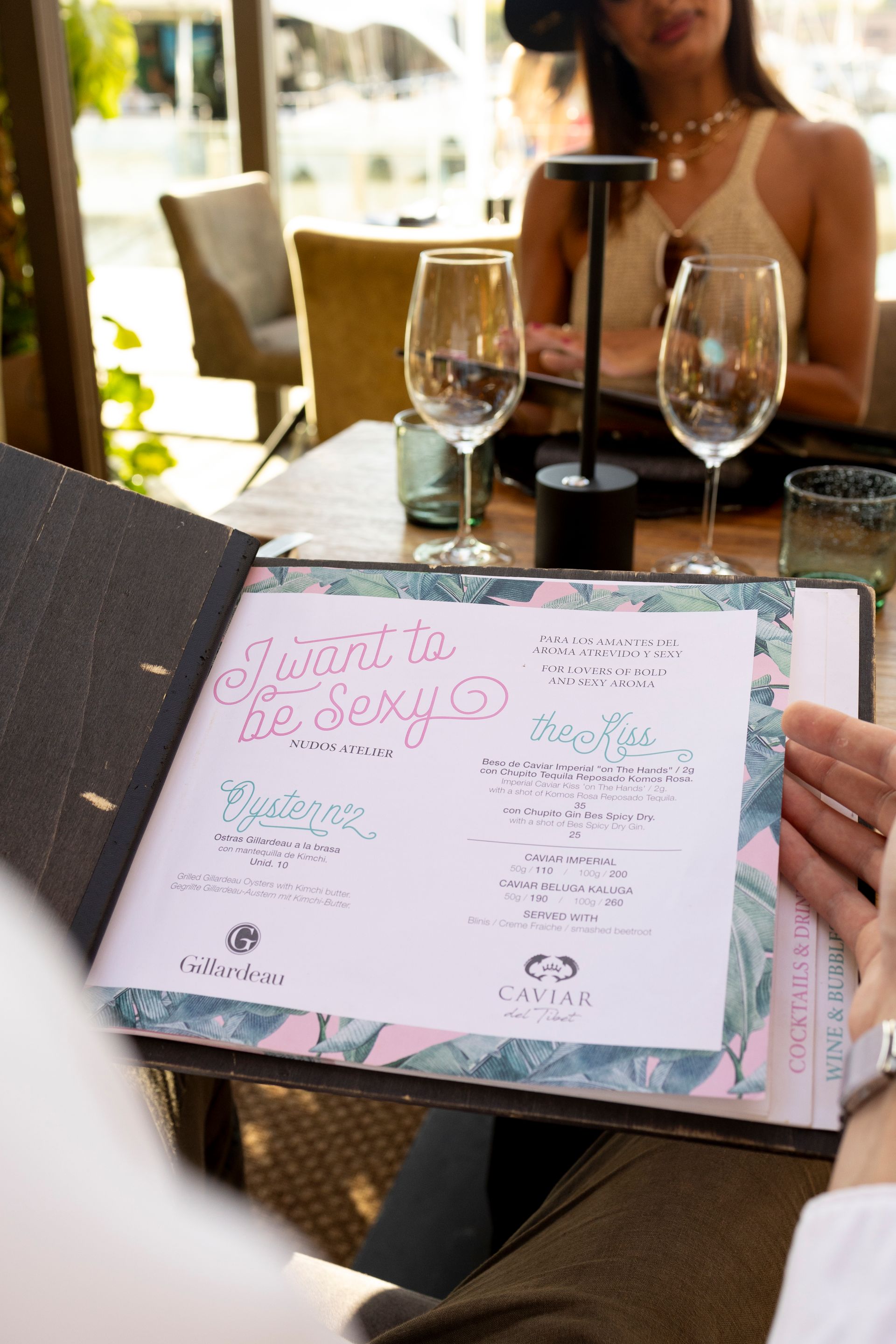A woman sits at a table looking at a menu