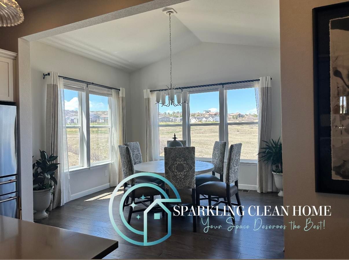 Dining room with a table and chairs next to a window, with a logo in the foreground.