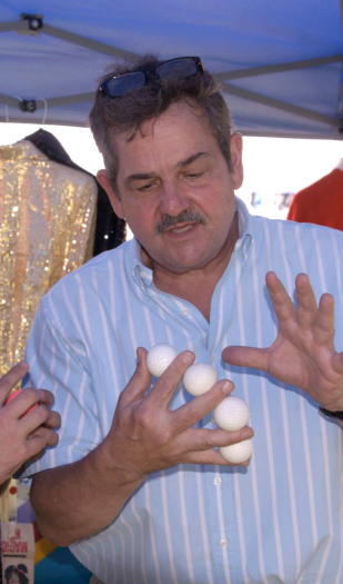 A man in a striped shirt is holding three eggs in his hands
