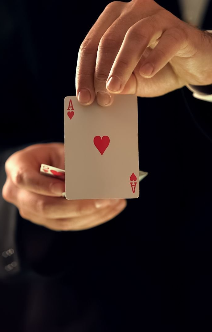 A person is holding an ace of hearts playing card