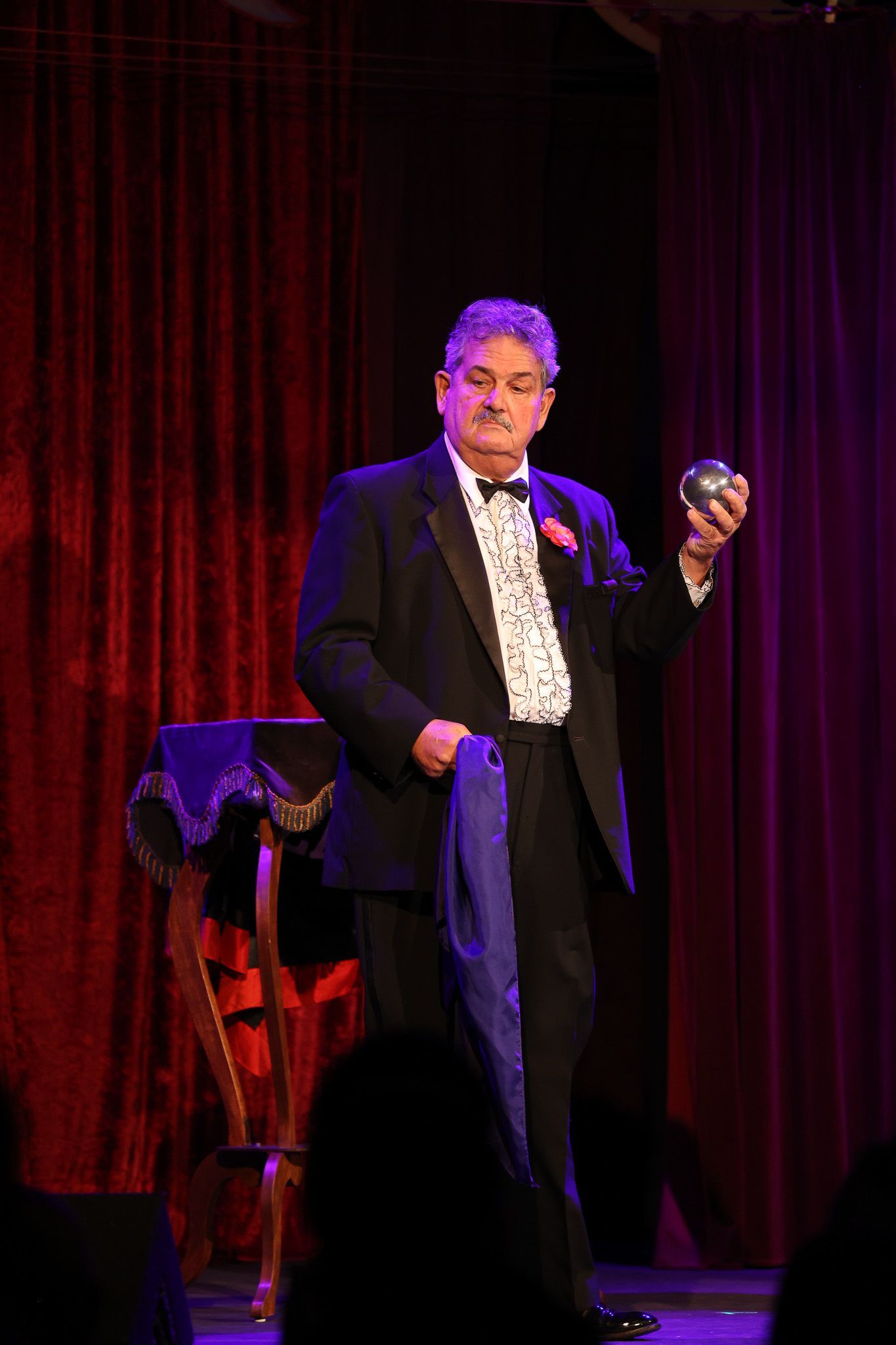 A man in a tuxedo is holding a ball on a stage.