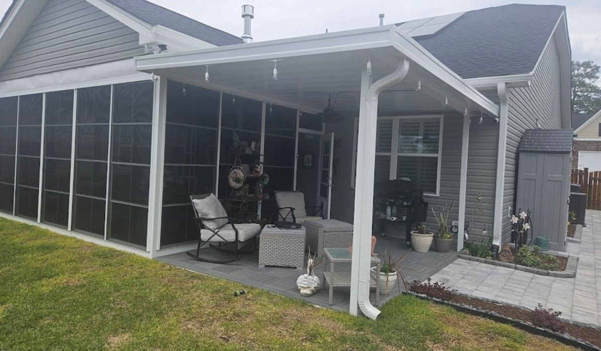 A house with a screened in porch and patio furniture.