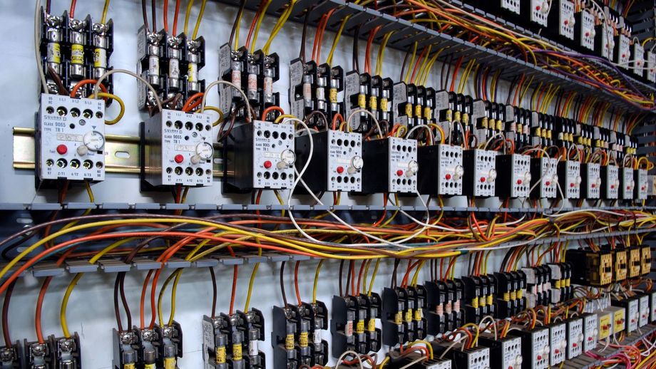 Row of electrical control panels with colored wires and switches in an industrial setting