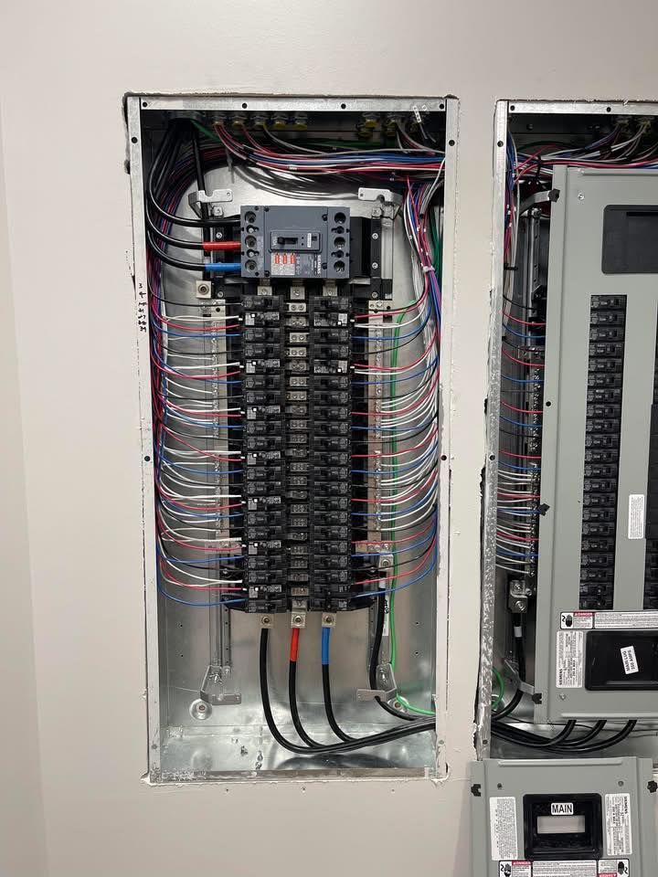 Open electrical breaker panel with rows of circuit breakers and colored wiring