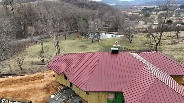 Red roofed building in a rural setting, trees and fields in the background.