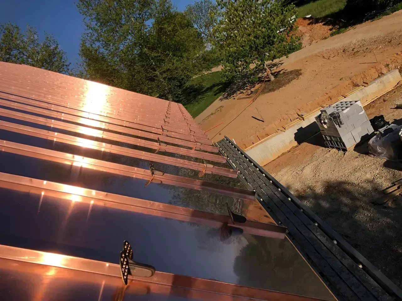 Copper roof being installed with reflective sunlight; construction site.