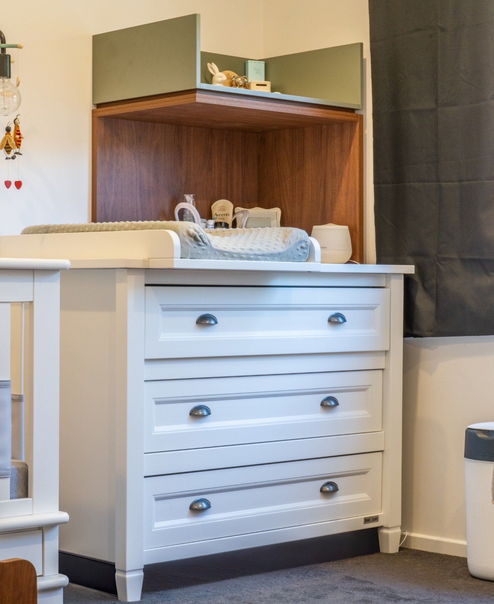 A white dresser with drawers and a changing table in a nursery