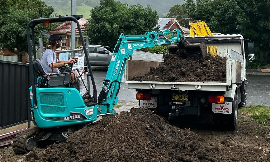 mini excavator loading dirt in truck