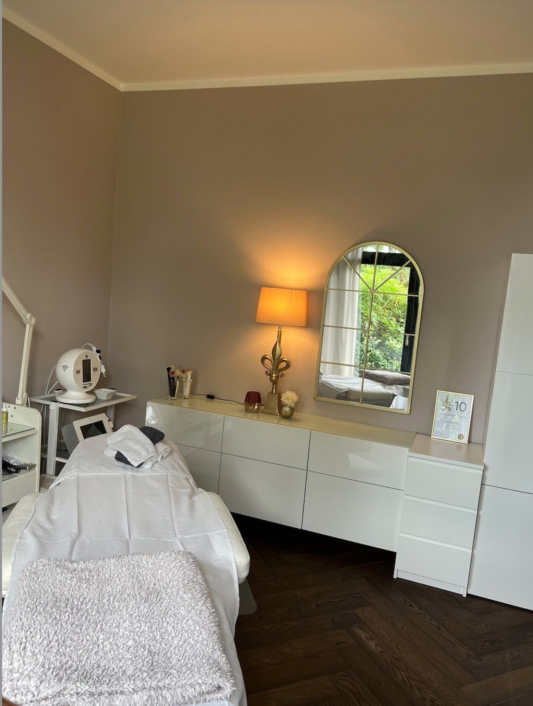 Ein Zimmer mit Bett, Spiegel, Lampe und Kommode.