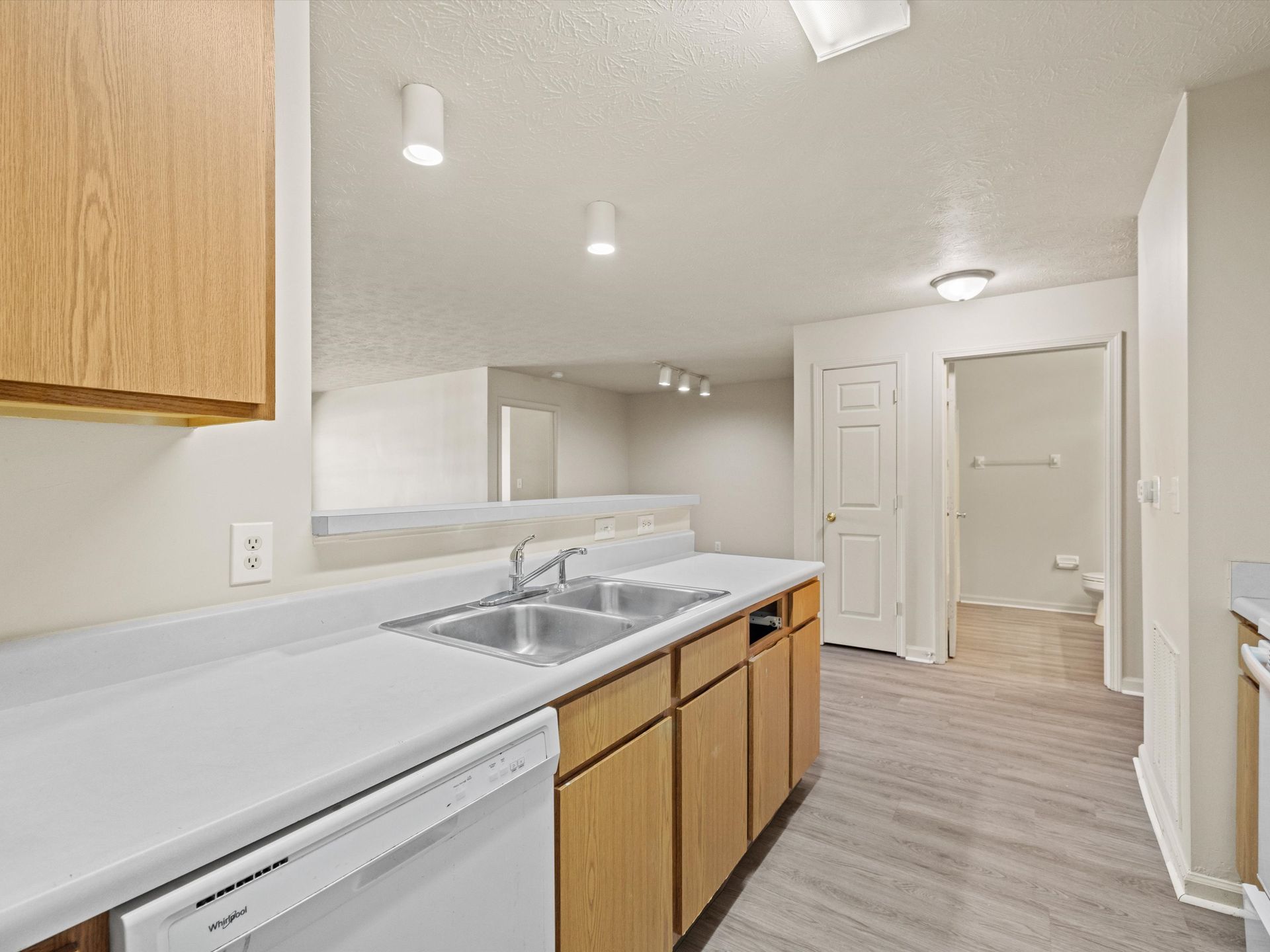 A kitchen with two sinks , a dishwasher , and wooden cabinets.