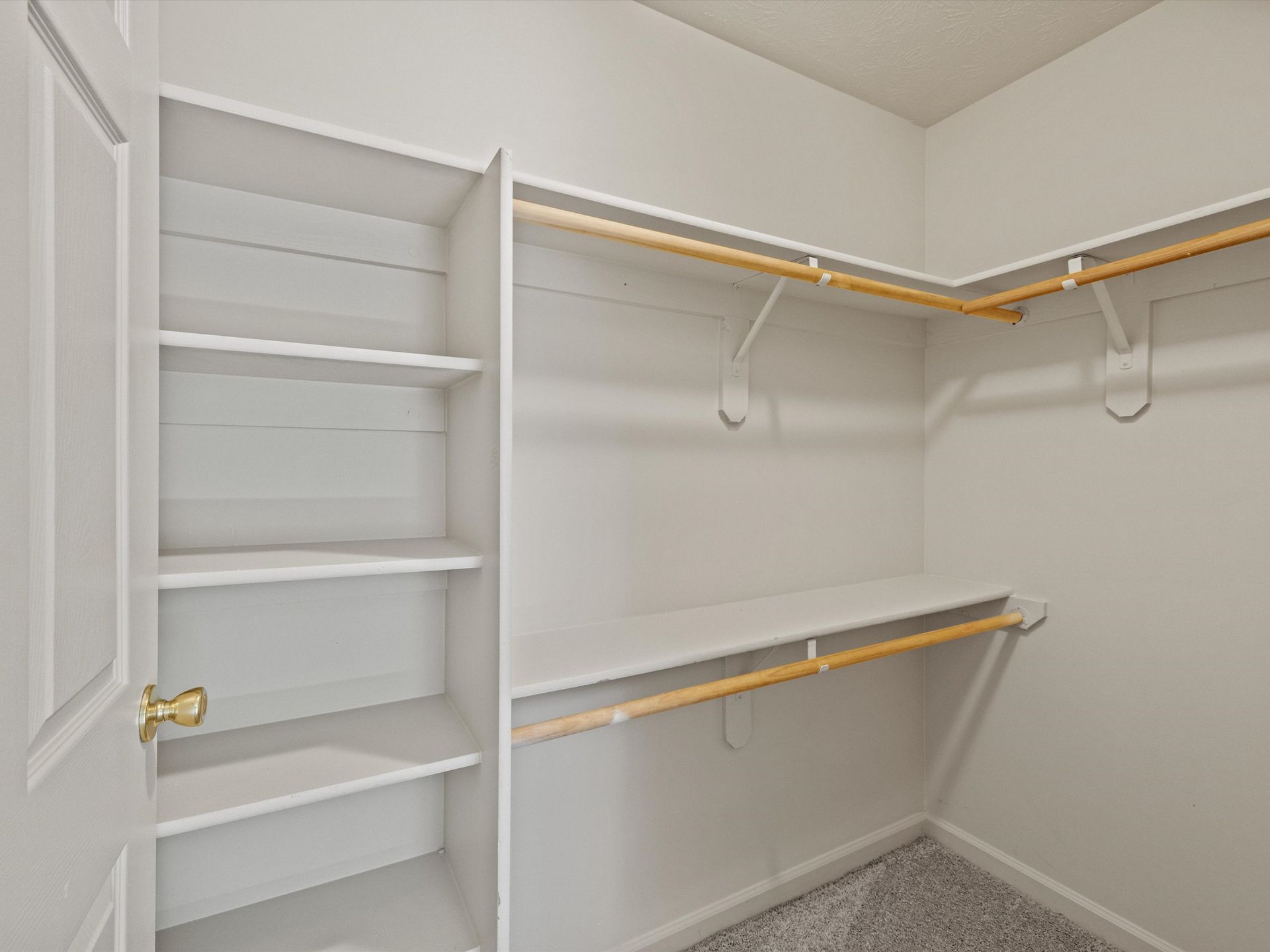 An empty walk in closet with shelves and clothes racks.