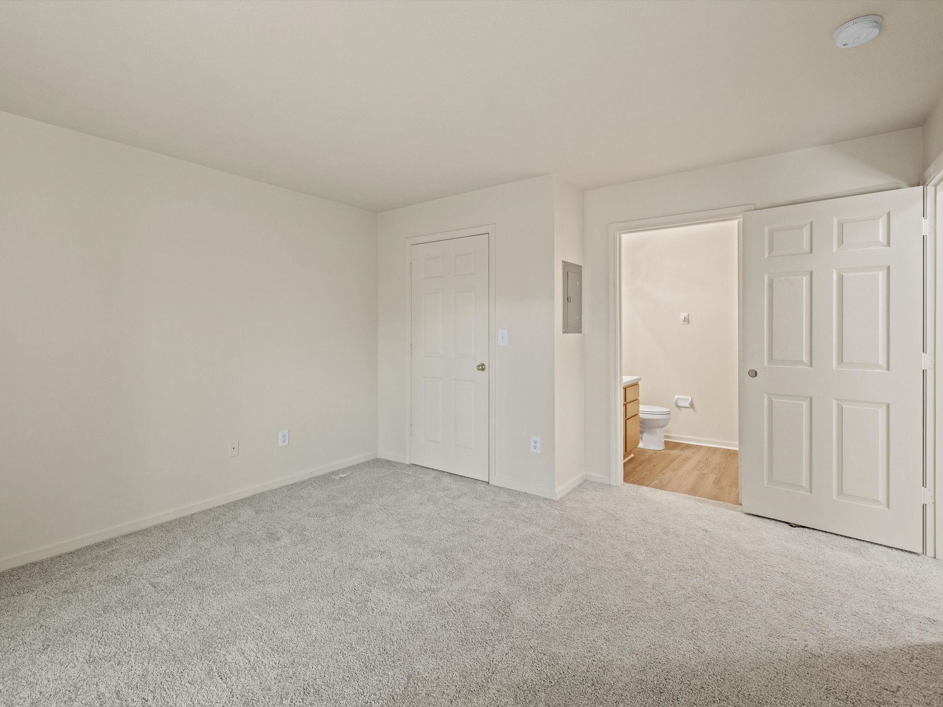 An empty bedroom with a toilet and a closet with view of bathroom.