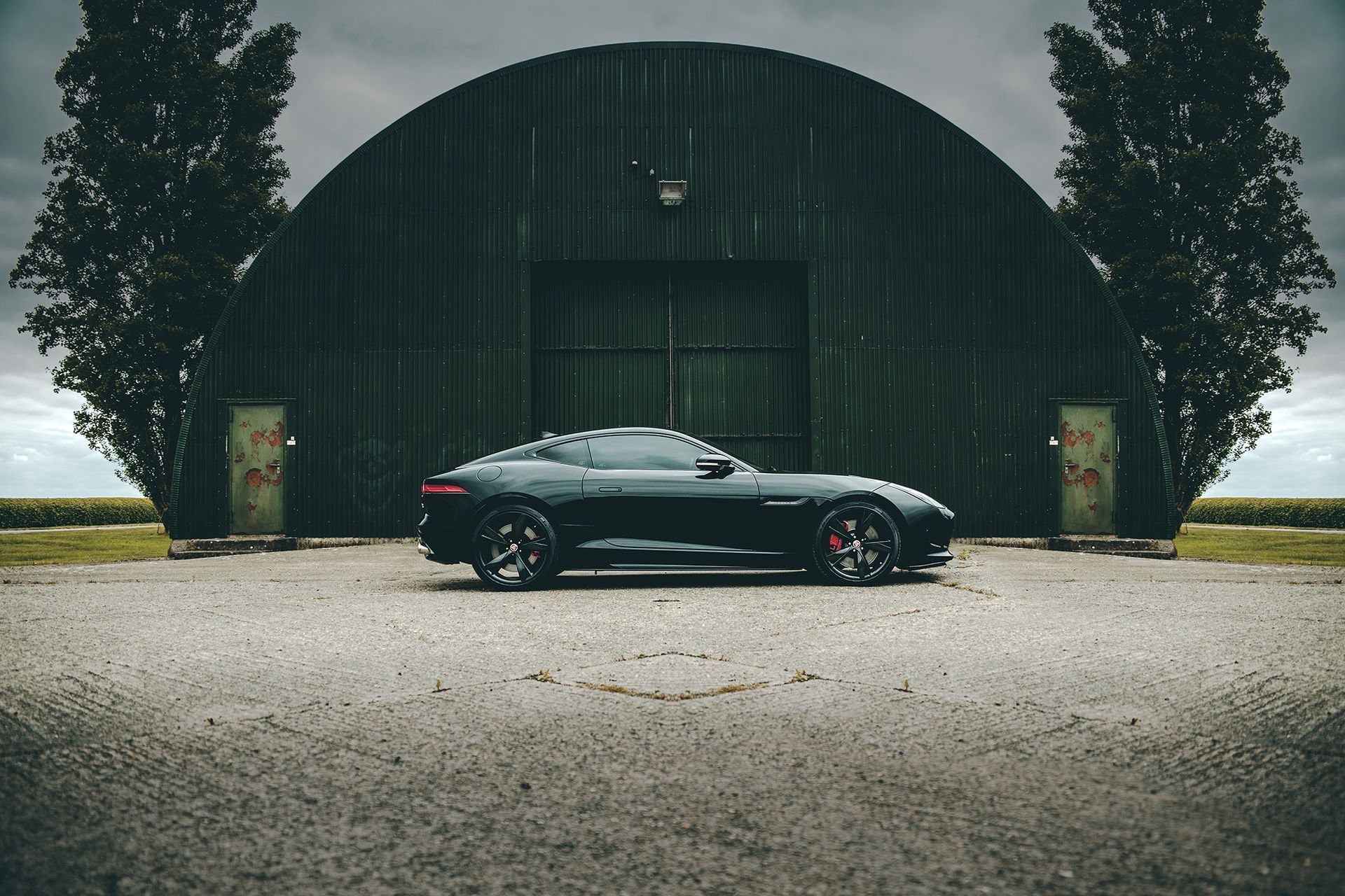 A black Jaguar F Type parked in front of a large building shot by Dammo Photography