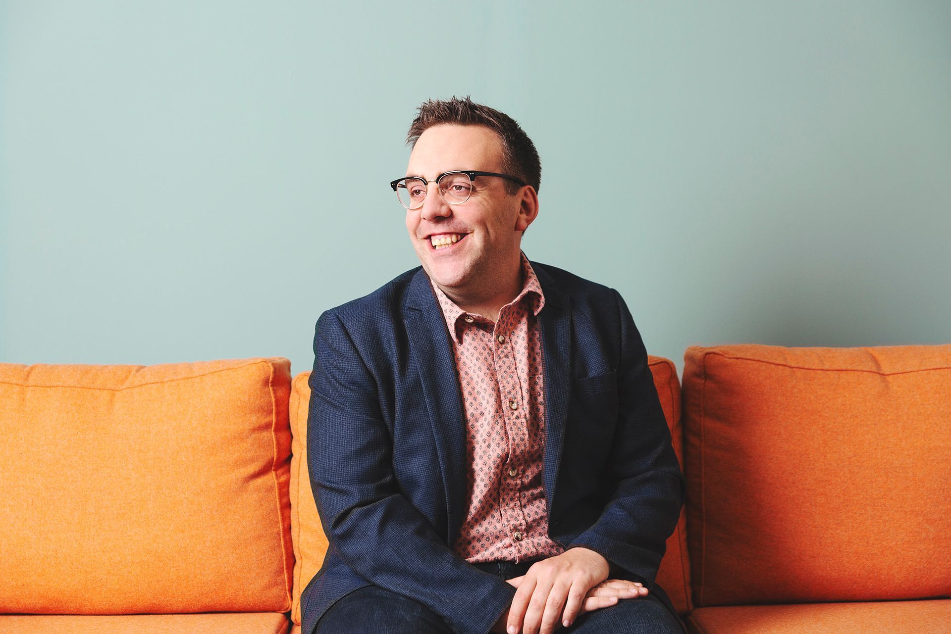 Portrait of a smart professional man sitting on an orange sofa shot by Dammo Photography