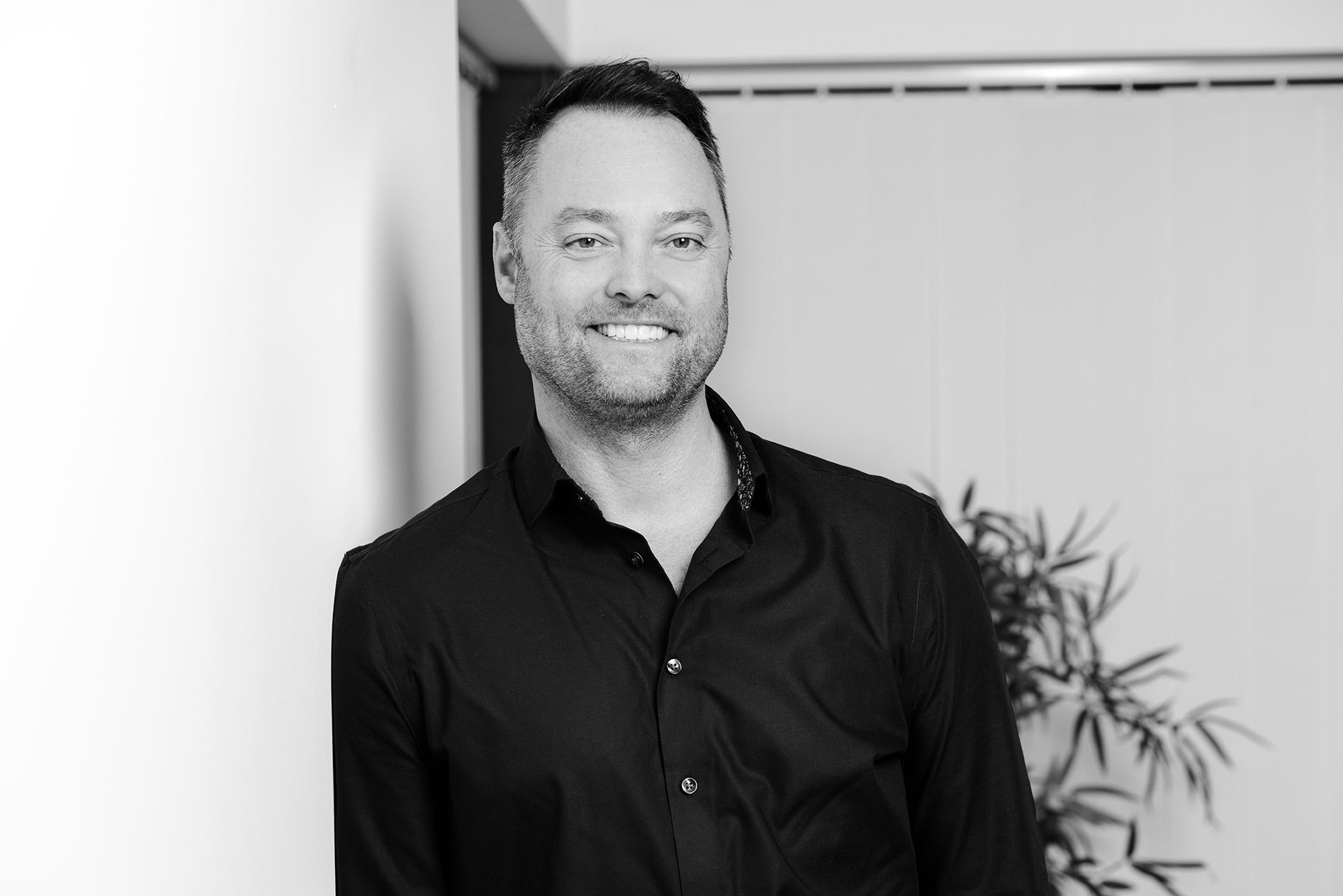 Black and white Portrait of a smart professional man leaning against a wall shot by Dammo Photography