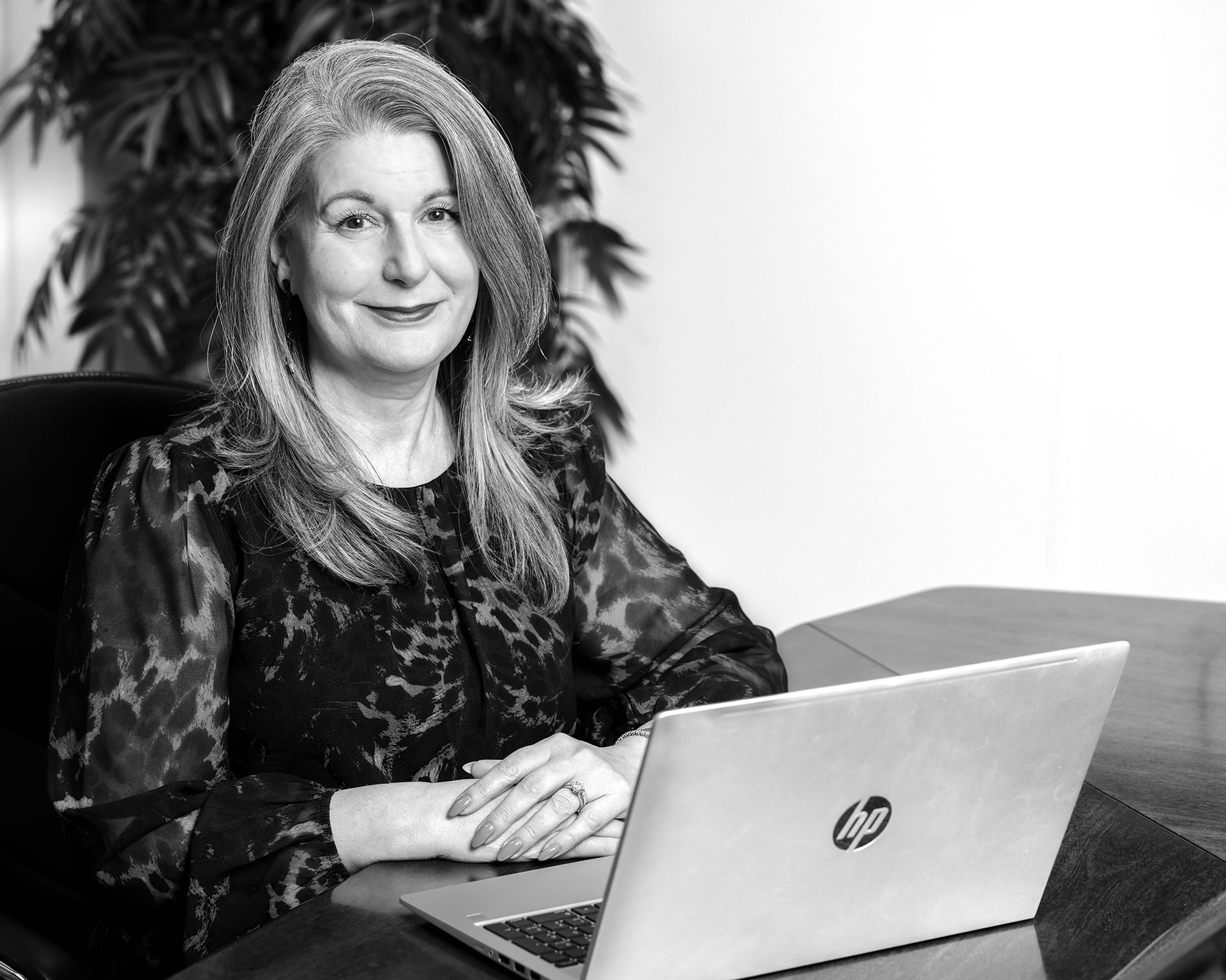 Black and white Portrait of a smart professional woman sat at a desk with her laptop shot by Dammo Photography
