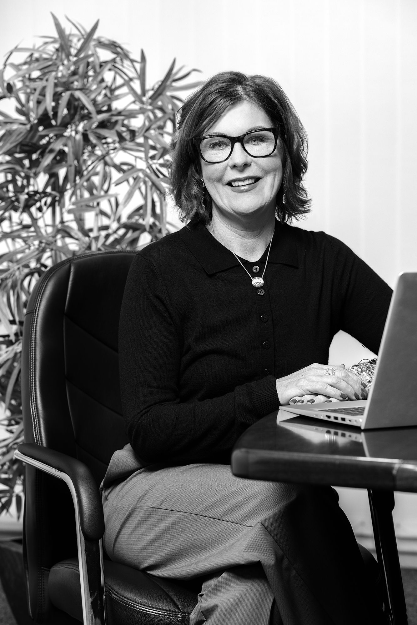 Black and white Portrait of a smart professional woman sat at a desk with her laptop shot by Dammo Photography