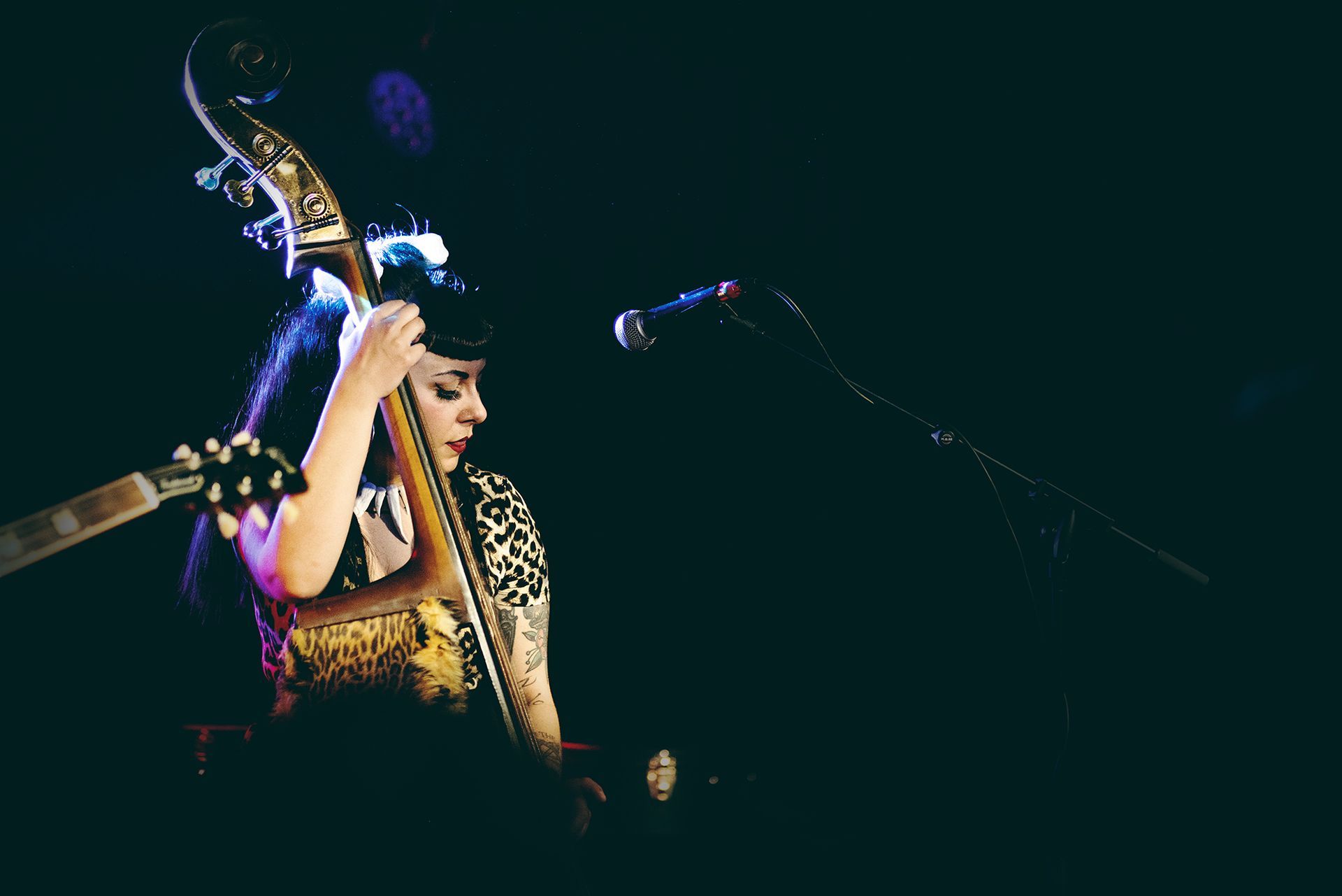 A woman is playing a double bass and singing into a microphone shot by Dammo Photography