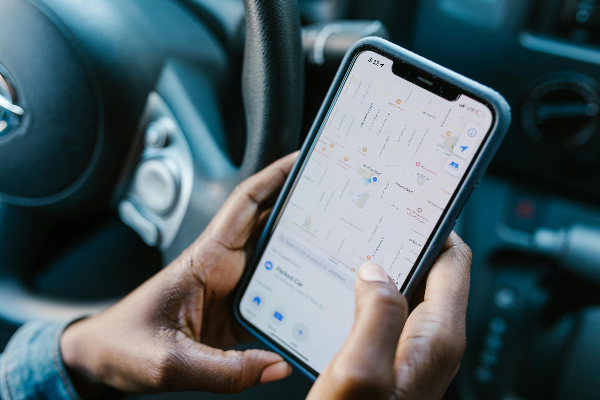 Hands holding a smartphone with a navigation map open inside a car