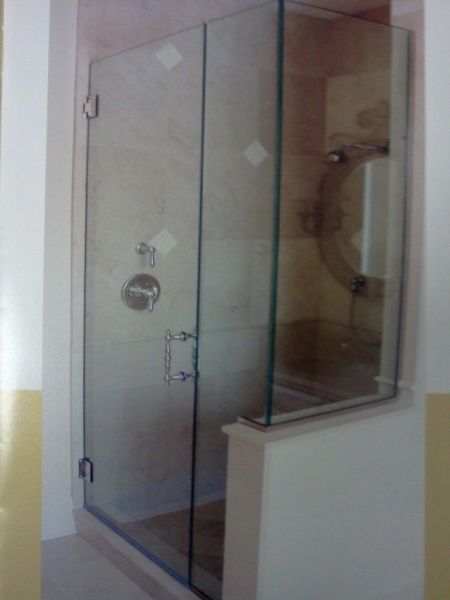 A bathroom with a glass shower door and a mirror.