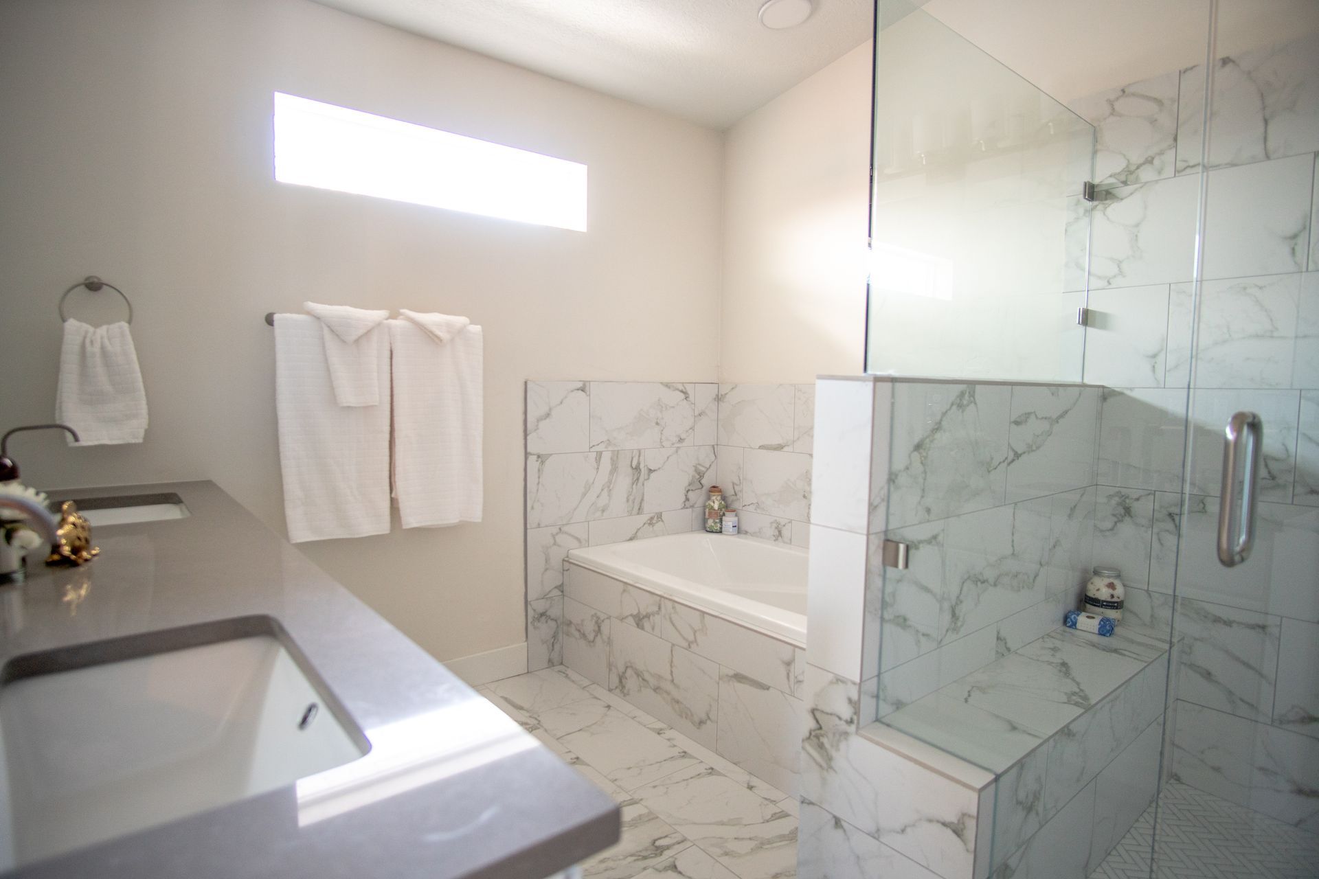A contractor points up as a couple surveys a room with large windows, under construction, wood beams, and a view of a yard.